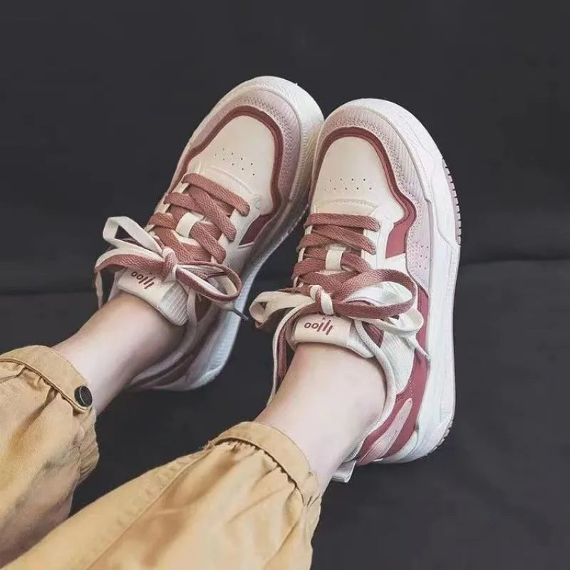 Women's beige and pink low-top lace-up sneakers with a rubber sole on a white background.