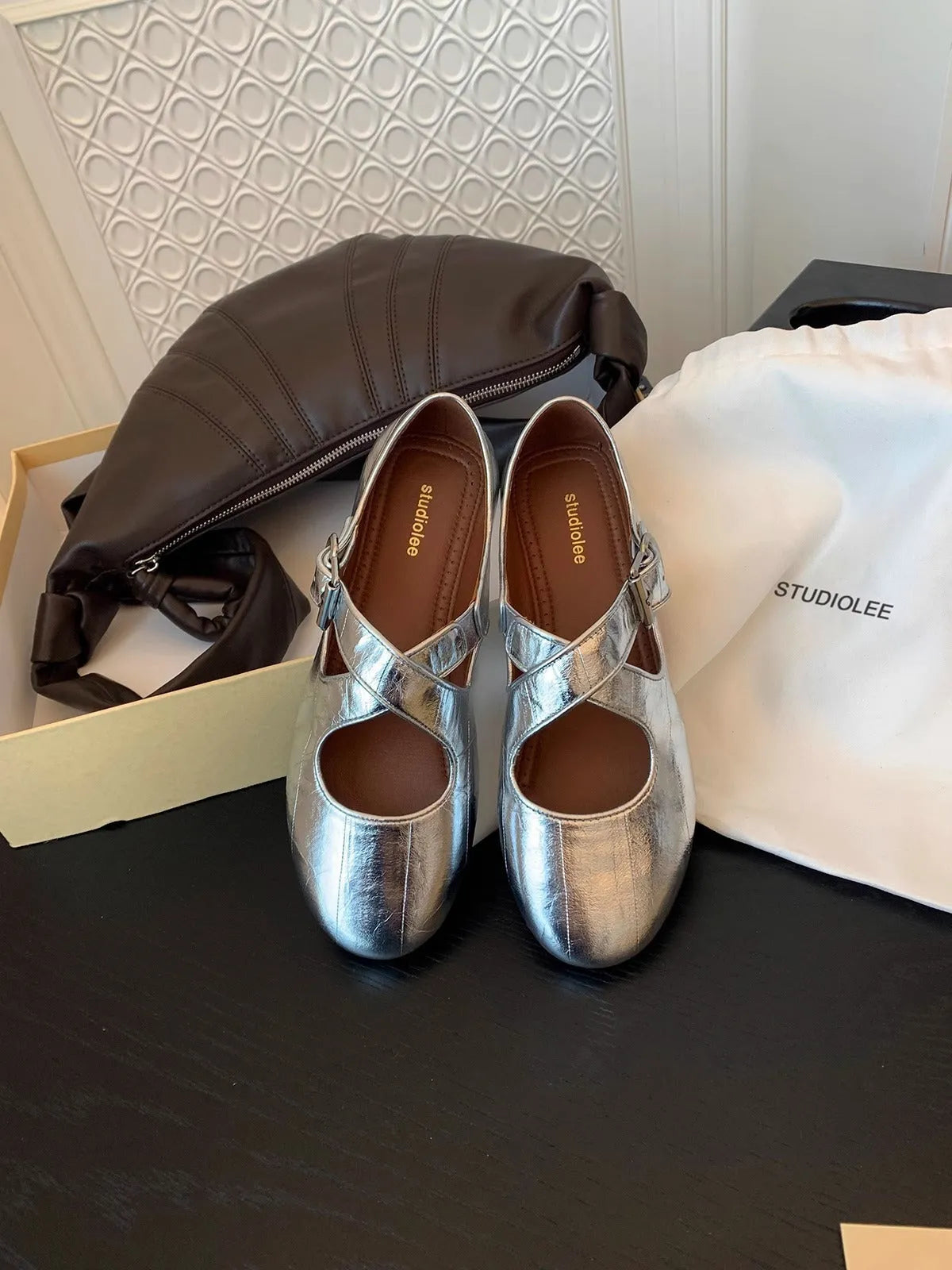 Silver women's cross strap buckle round toe cowhide leather flat pumps on a plain background