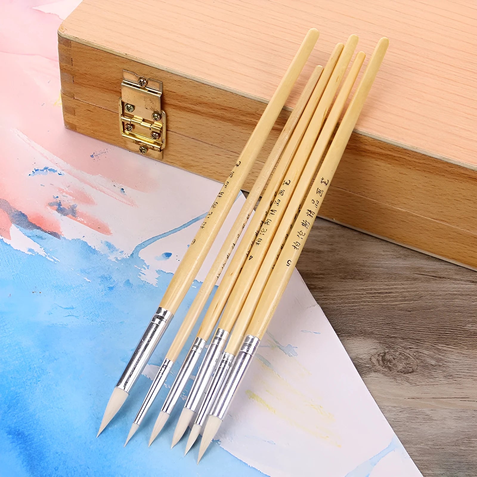 Set of six wooden handled hook line pen brushes with wool pointed tips on a white background.