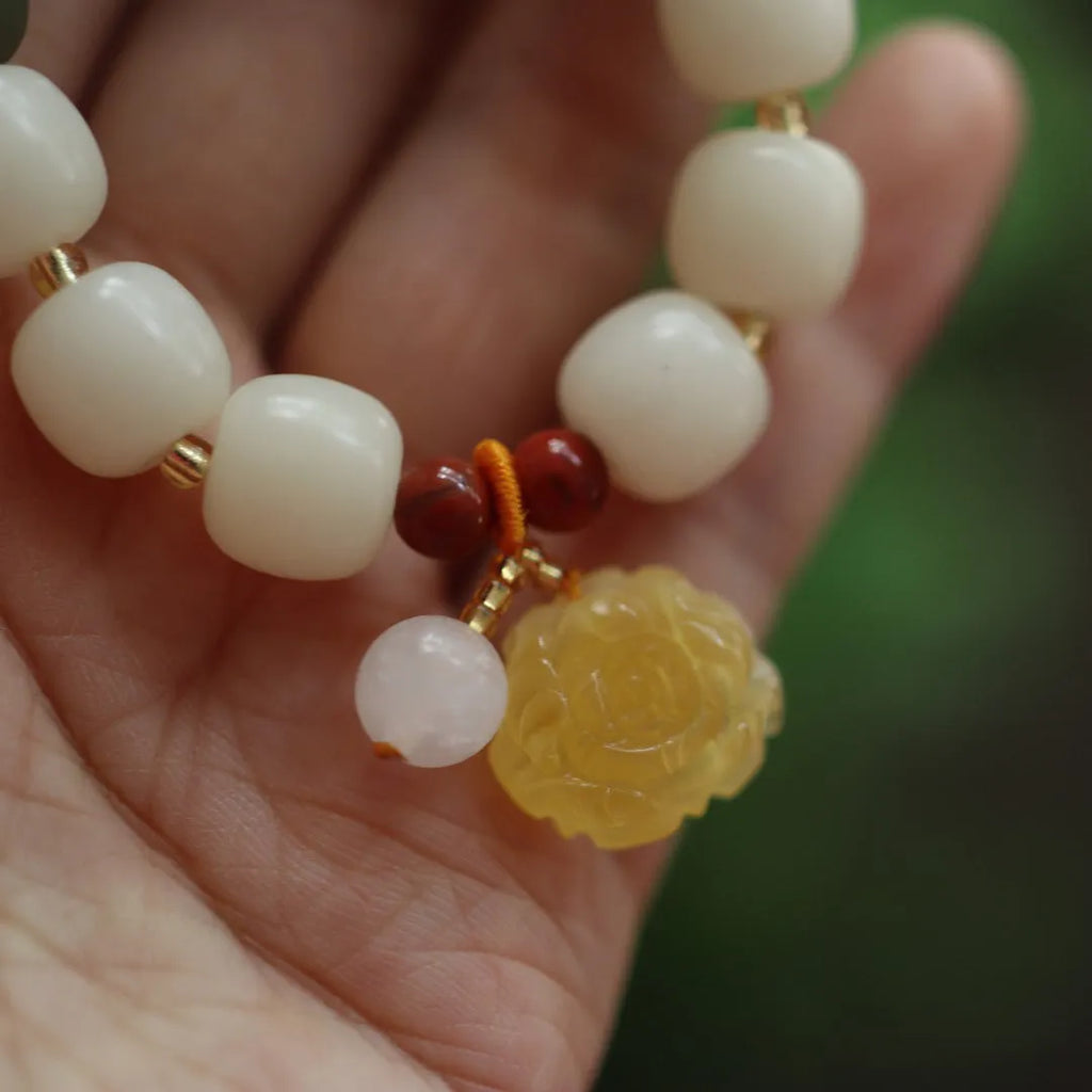 Close-up of a woven gradient white jade and Bodhi root bracelet with flower-shaped beads and a lotus accent.
