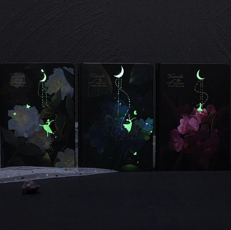 A5 notebook with luminous illustrated cover in blue, shown open on a desk.
