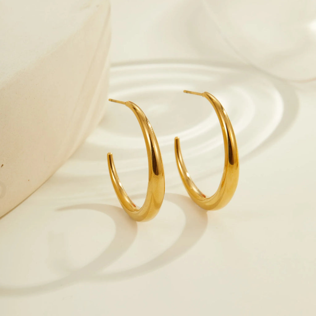 Simple round titanium steel hoop earrings for women in gold and steel finishes, shown in small and large sizes.