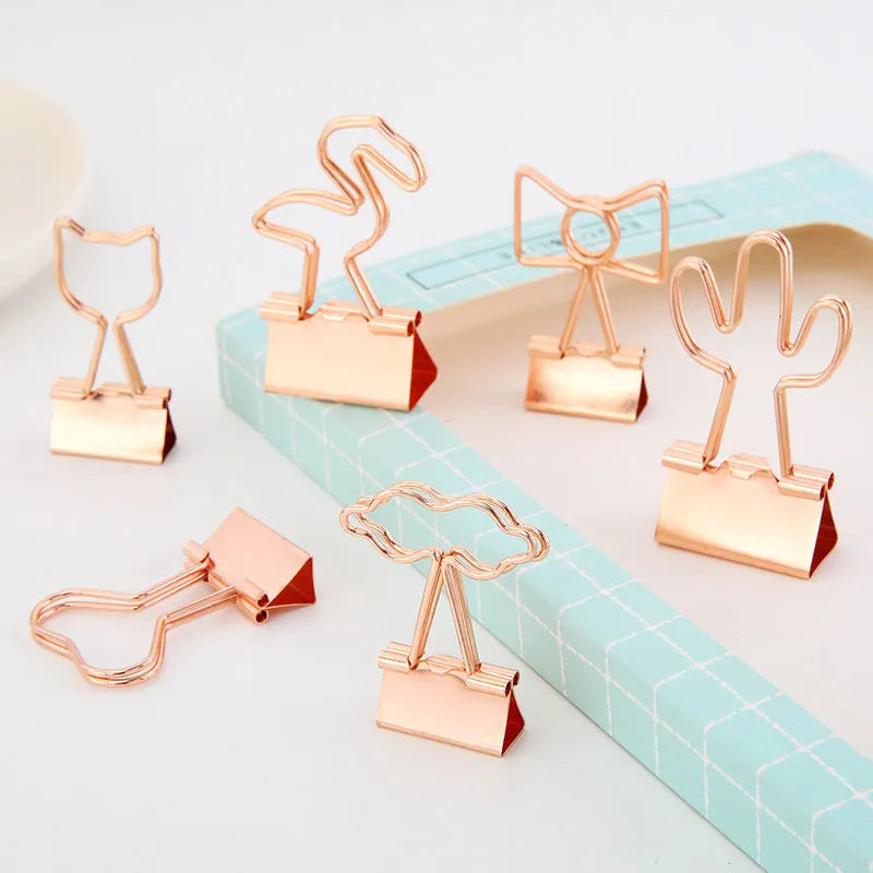 Gold metal decorative paper clip in a bow shape with a long tail design.