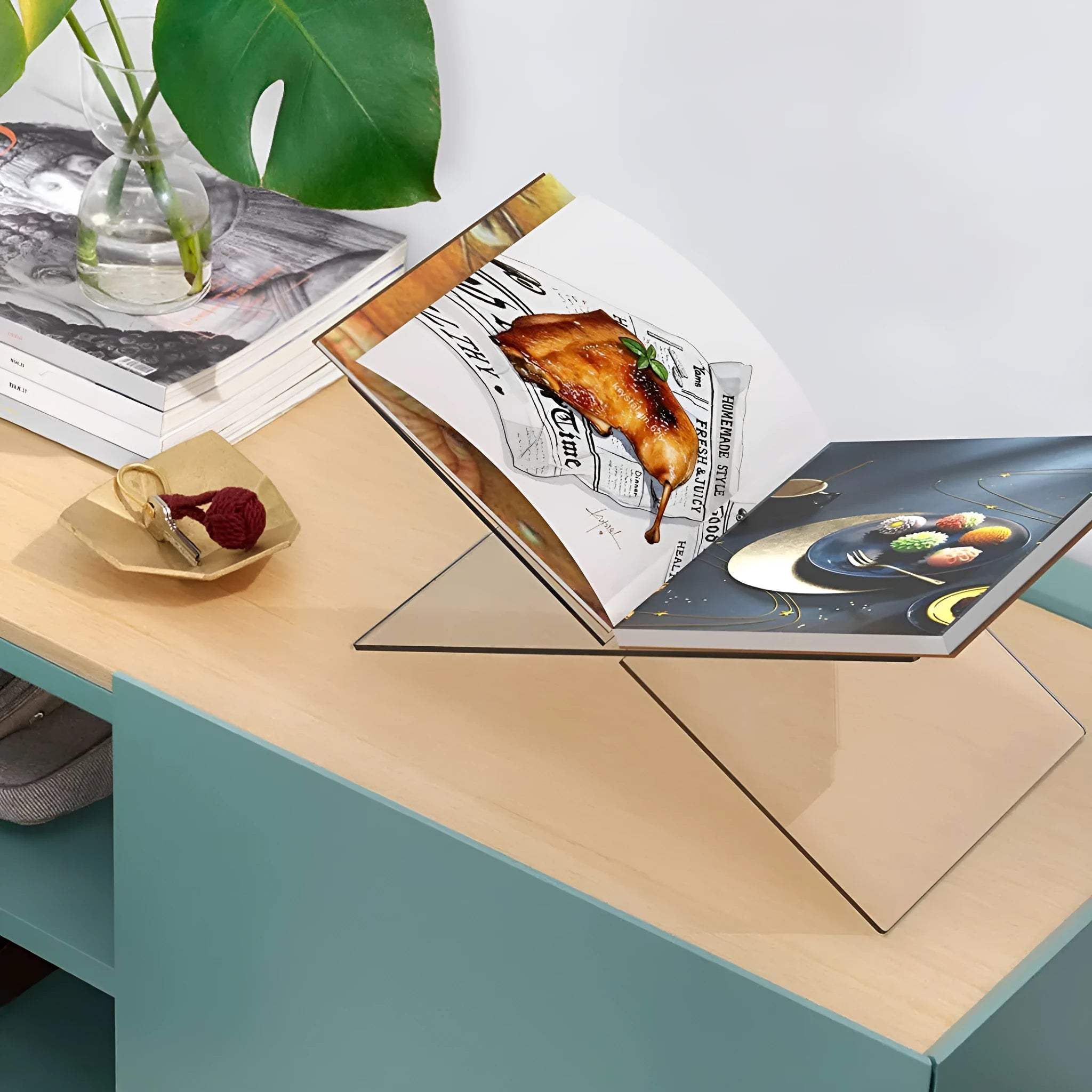 Clear acrylic X-shaped book reading rack displaying a book on a desktop