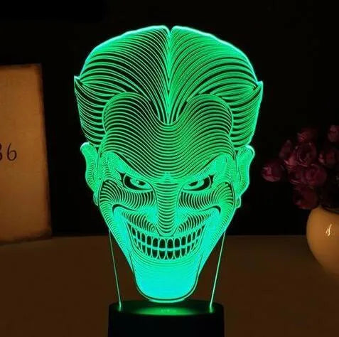 3D acrylic LED lamp displaying coloured light on a desk, with a remote control and USB cable