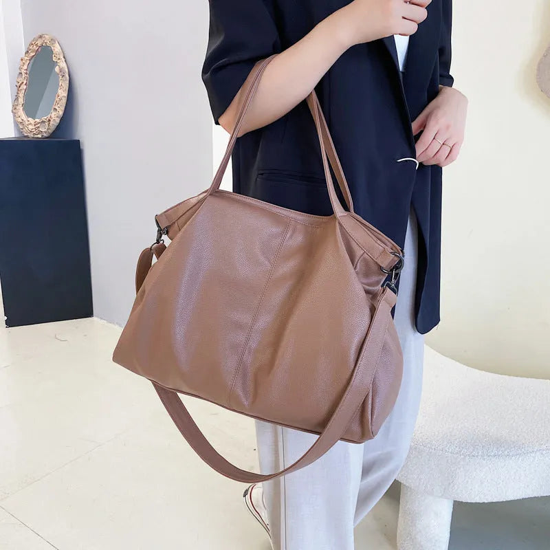 Soft black casual messenger tote bag with zip, showing internal phone pocket and adjustable long shoulder strap.