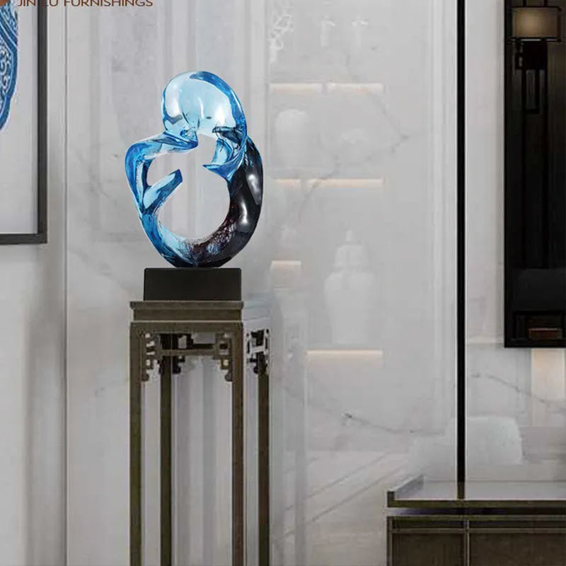 A transparent resin sculpture ornament in a modern style, shown in blue and orange red colour options.