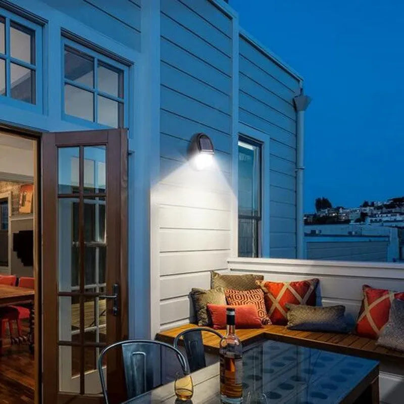 Black rectangular LED solar wall light with solar panel, shown mounted on an outdoor wall.