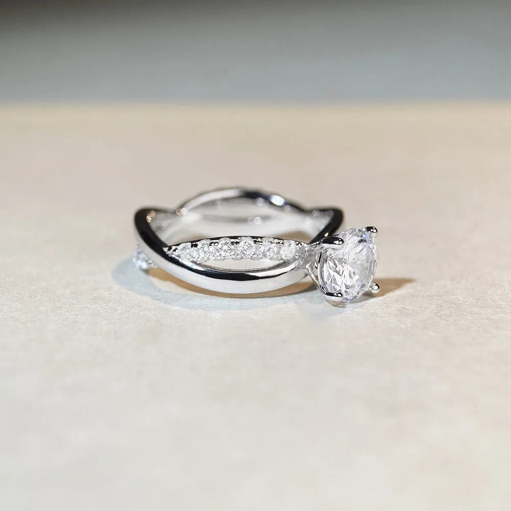 Geometric silver ring with a 1 karat moissanite in a four-claw setting, showing twisted band and cross design.