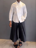 White asymmetric front long sleeve shirt paired with black pleated pants in a women's casual co-ord set.