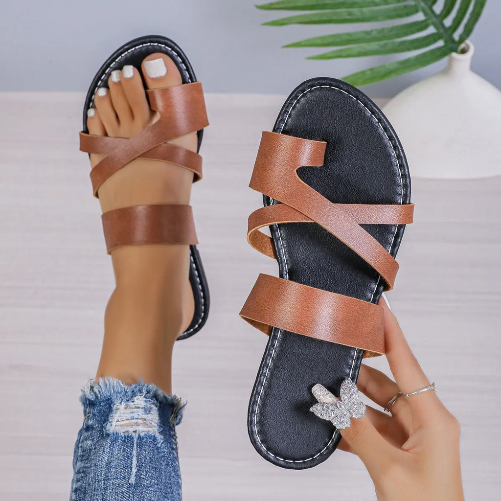 A pair of casual one-line beach slippers in a solid colour with a hollow-out pattern and rubber sole.