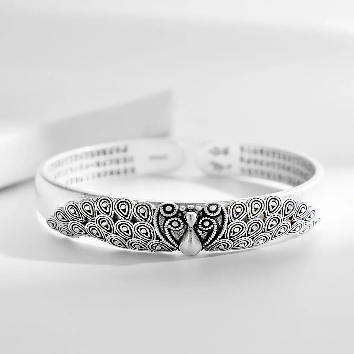 Antique copper plated silver bracelet with peacock open screen design on white background