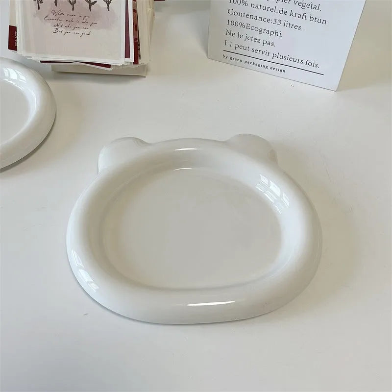 White round porcelain plant plate with a bear doodle design, shown under a small succulent pot.