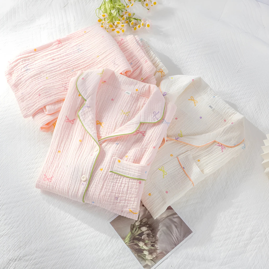 Women's pink cotton long-sleeved pajama top and trousers set laid flat.