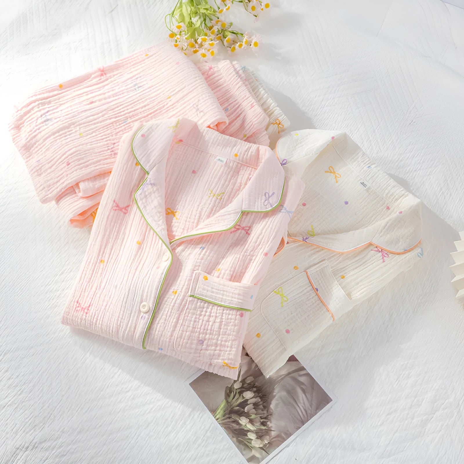 Women's pink cotton long-sleeved pajama top and trousers set laid flat.