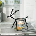 Wrought iron fawn candle holder in gold finish with glass cup on a table