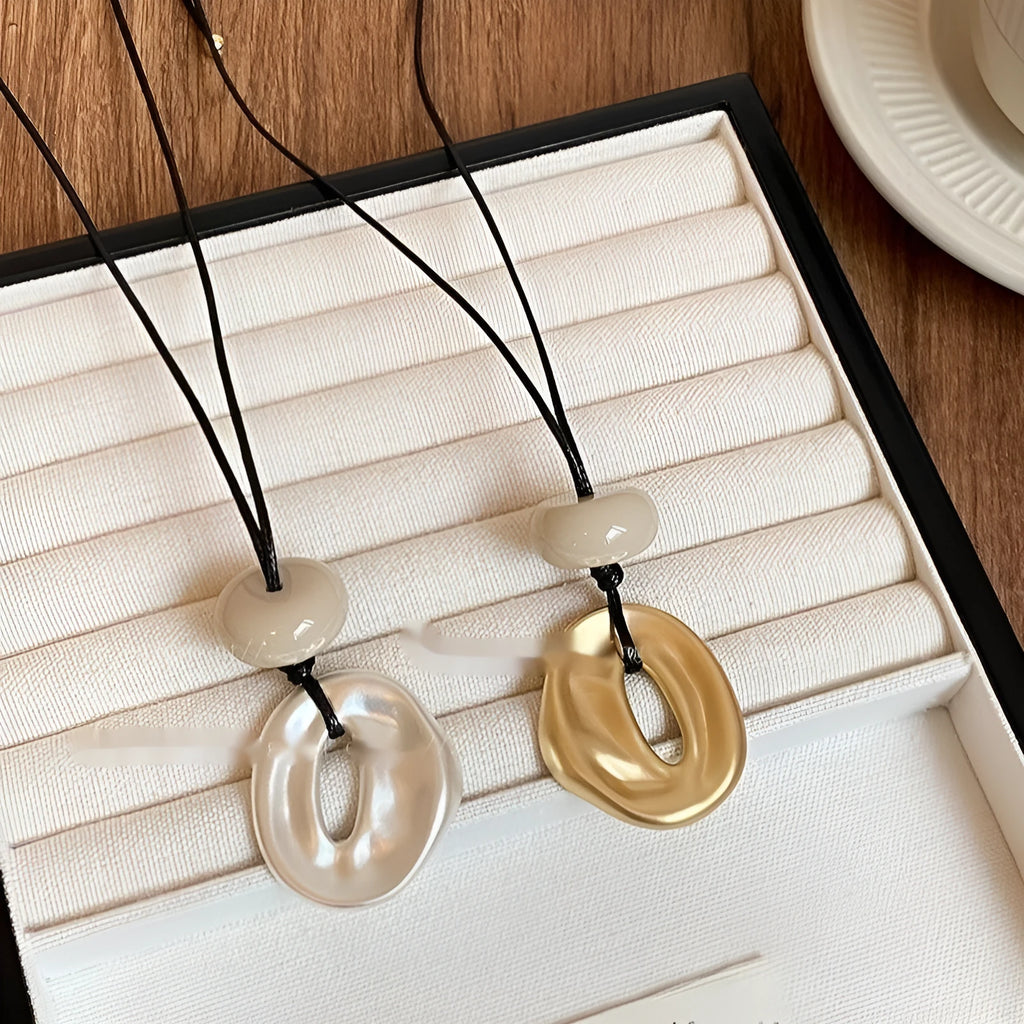 Gold long geometric bow pendant necklace with artificial crystal accents on a white background