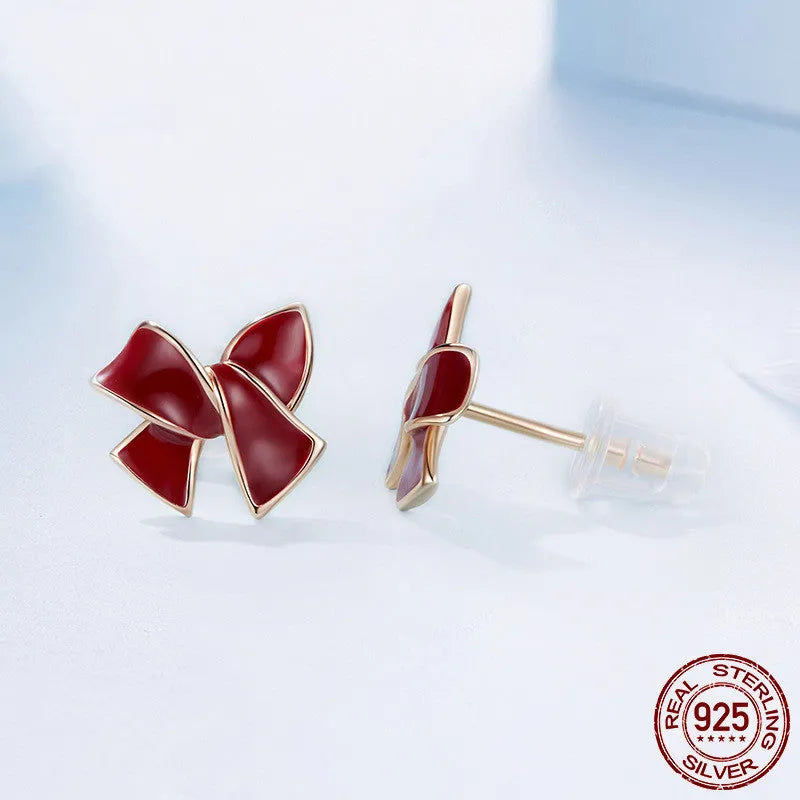 Pair of silver 925 sterling silver bow stud earrings with wine red finish on white background