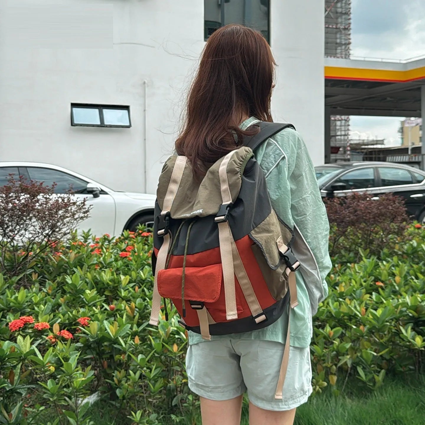 Orange and green contrast colour large nylon backpack with multiple compartments on a plain background.
