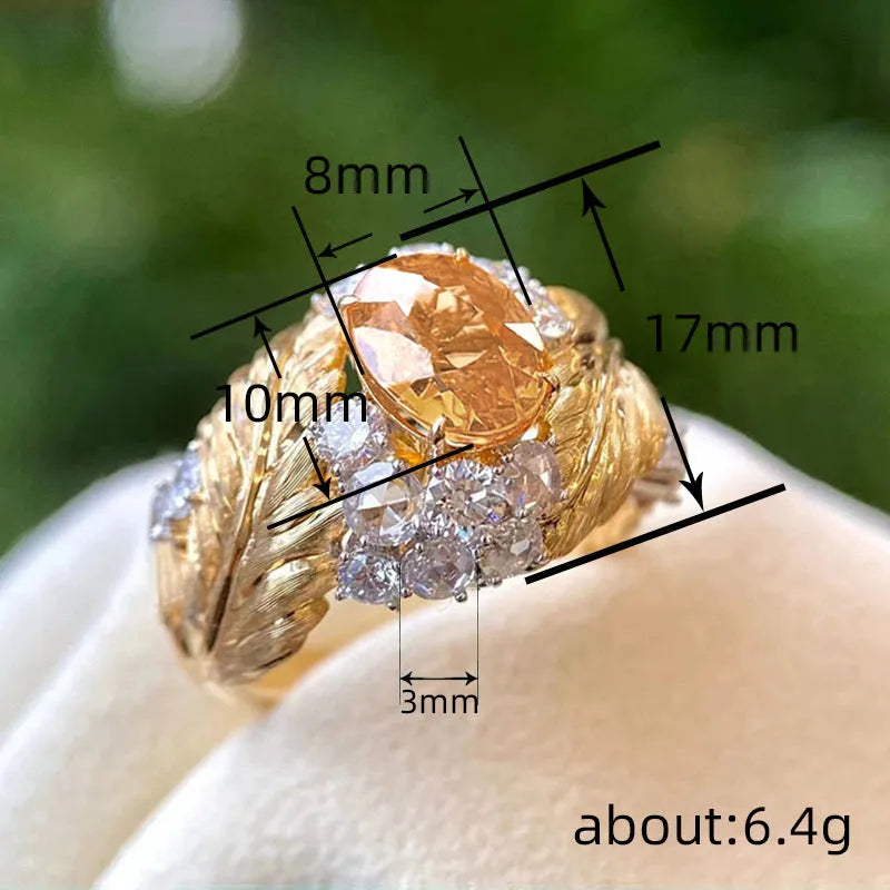 Gold women's ring with embossed feather pattern and a yellow zircon stone on a geometric copper band.