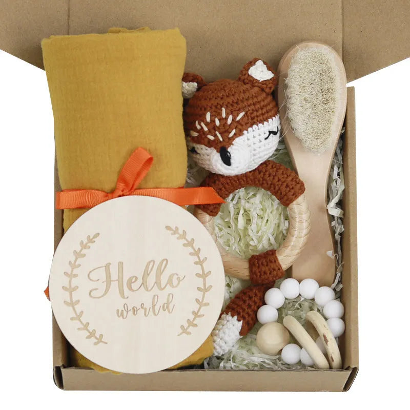 Baby teething toy gift set with bamboo blend gauze blanket, wooden beech bell, teether, brush, and milestone marker.