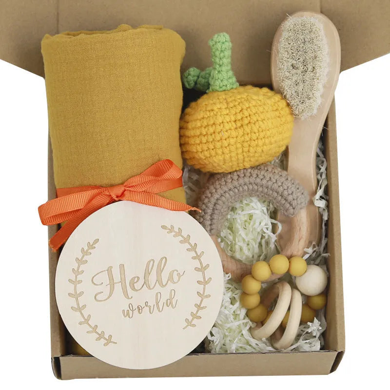Baby teething toy gift set with bamboo blend gauze blanket, wooden beech bell, teether, brush, and milestone marker.