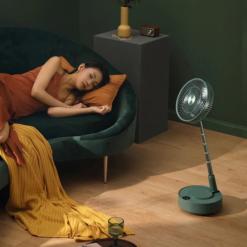 Green telescopic floor fan extended to full height with remote control resting beside base