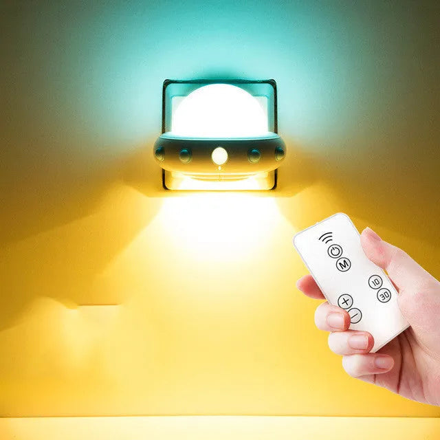 Remote control UFO shaped bedside night light in blue, pink or white colours on a table