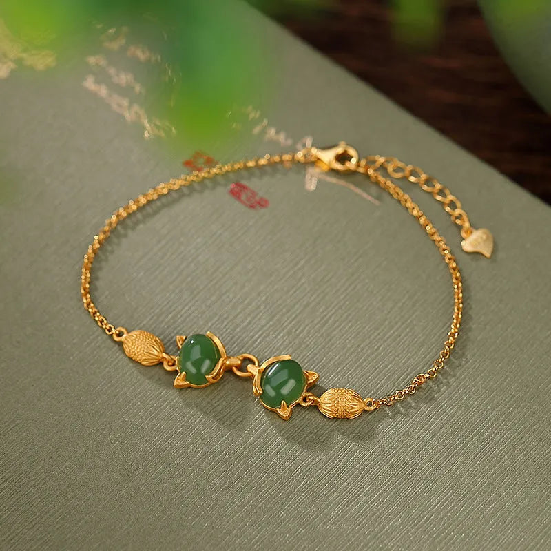 Close-up of a sterling silver fox charm bracelet with a Hetian jade stone on a model's wrist.