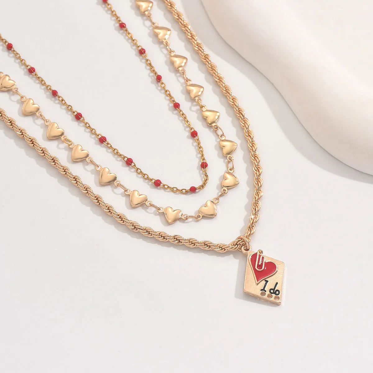Gold tone three-layer love necklace with geometric pendant on a model.
