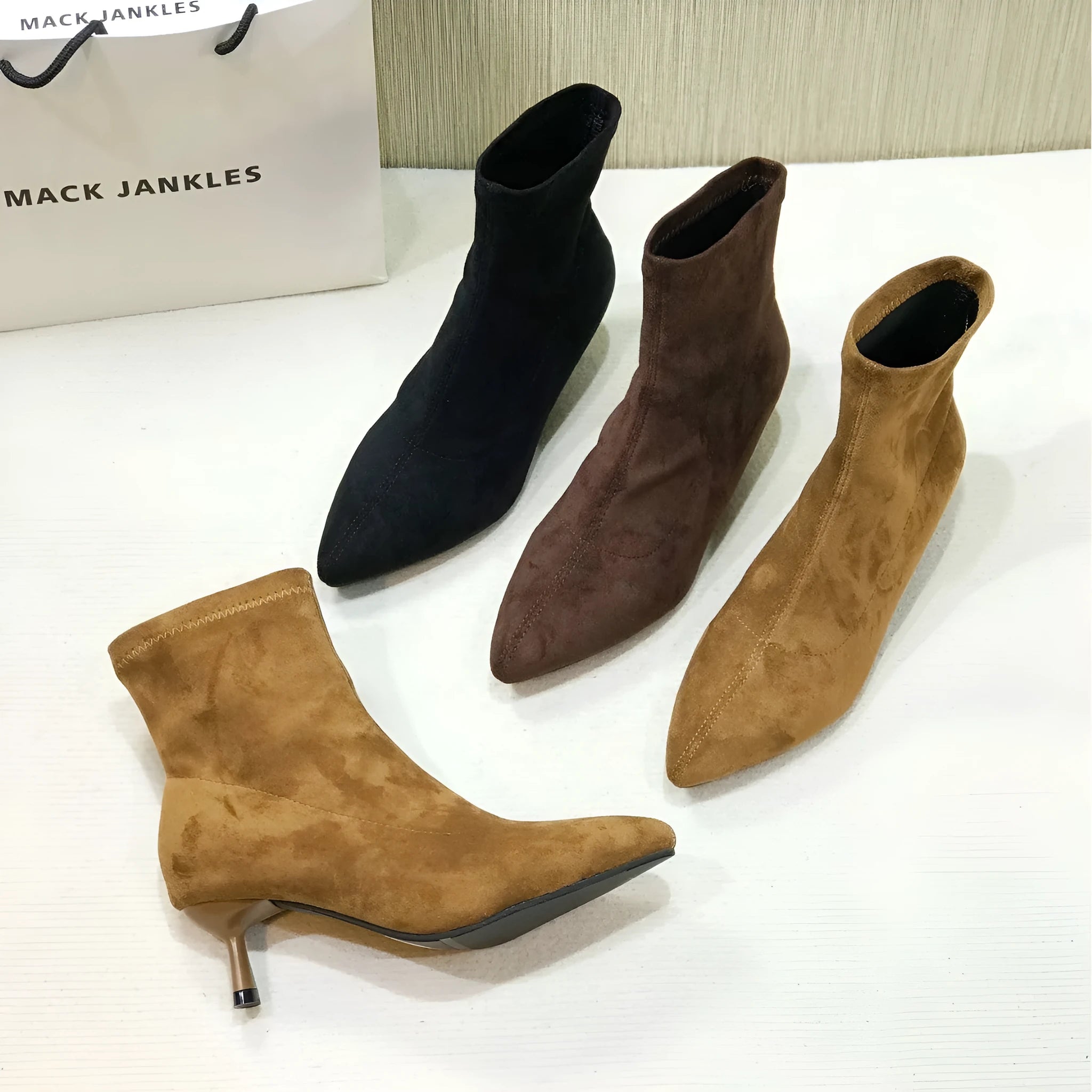 Women's black pointed-toe ankle boots with a stiletto heel and mid-calf sock length.