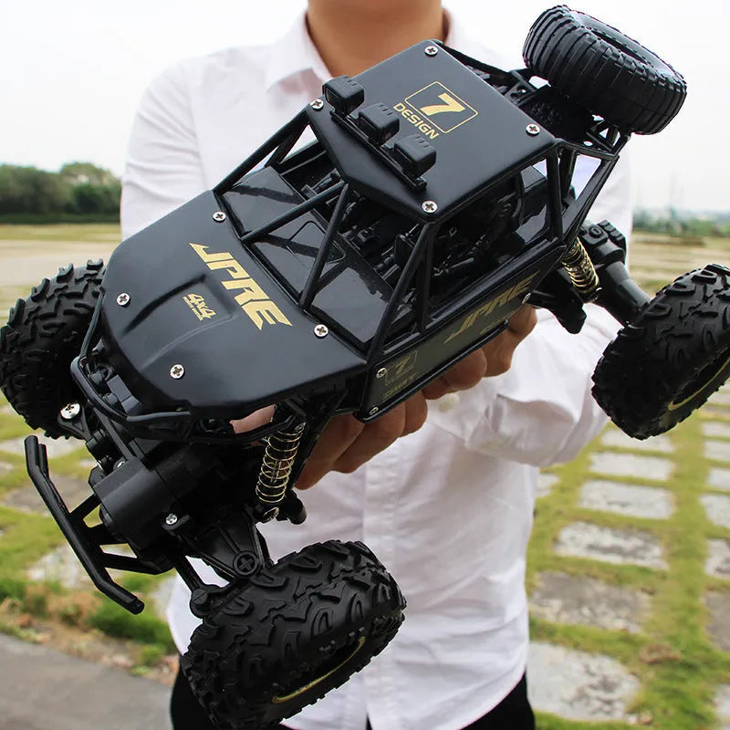 Large black 4WD remote control off-road climbing car on a rocky surface.