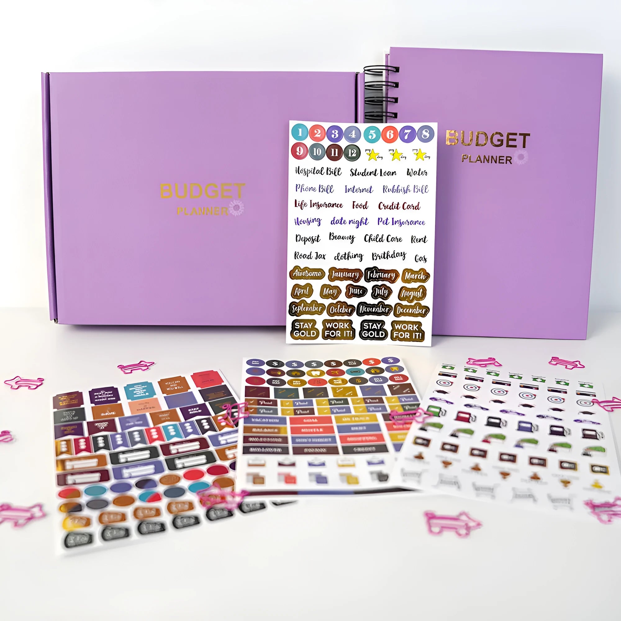 Purple coil-bound budget book with stickers and paper clips for monthly financial planning