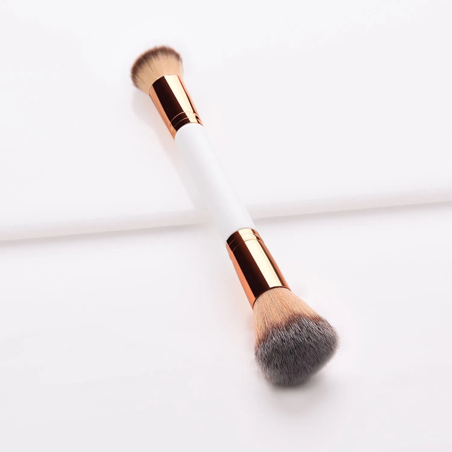 White double head makeup brush with wooden handle and nylon wool bristles on flat surface