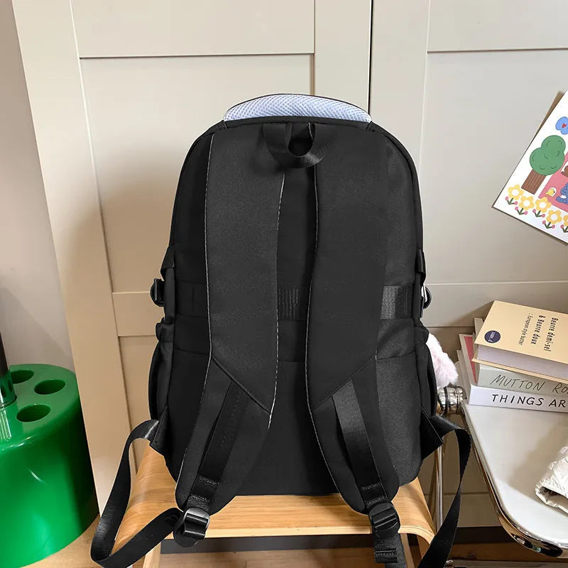 Nylon school backpack in green with pendant, showing curved shoulder straps and sewing line detail.