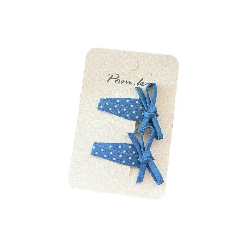 Children's denim handmade flower polka dot bow barrettes with triangle and duckbill clips on a light background