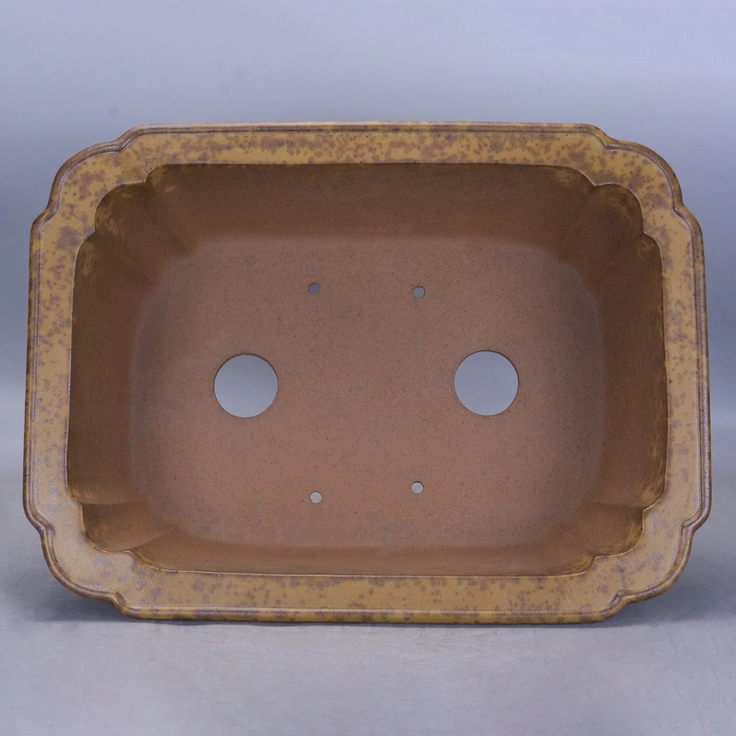 A large rectangular purple sand mud flowerpot with angled segment design on a floor.