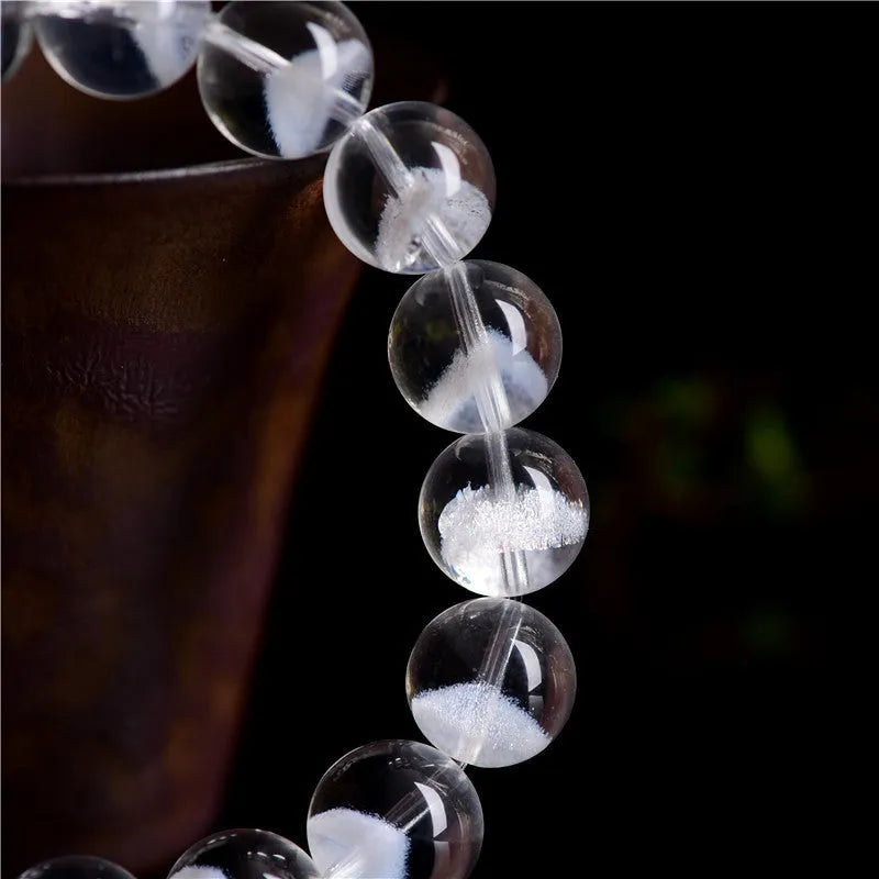 Women's white crystal pyramid bracelet with Ruyi symbols on wrist, showing ground bead texture.