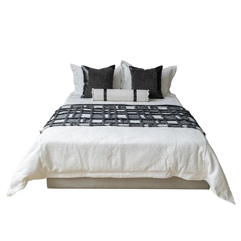 Modern minimalist grey and white plaid polyester bed runner set with pillowcase and round pillow on a bed.