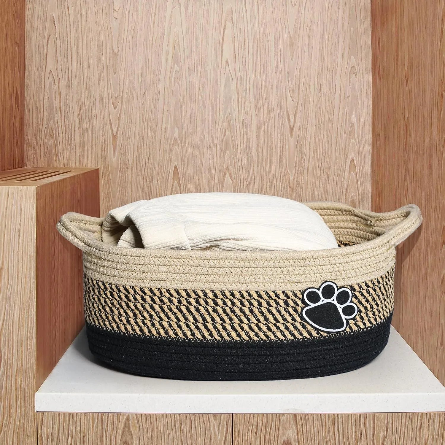 Handmade light beige woven cotton rope storage basket with a wooden handle.