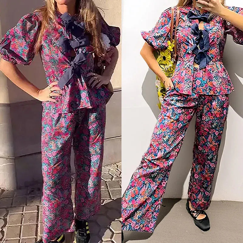 Women's floral print polyester trouser suit with puff sleeve blouse and matching trousers on a hanger.