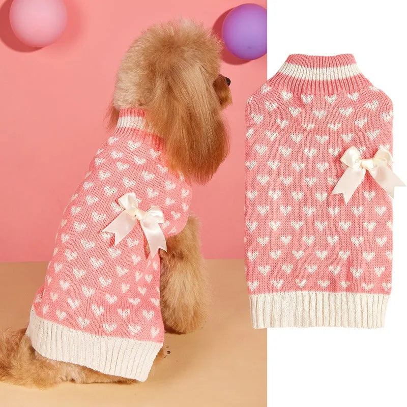 Red knitted dog jumper with a white love heart and bow design on a small dog
