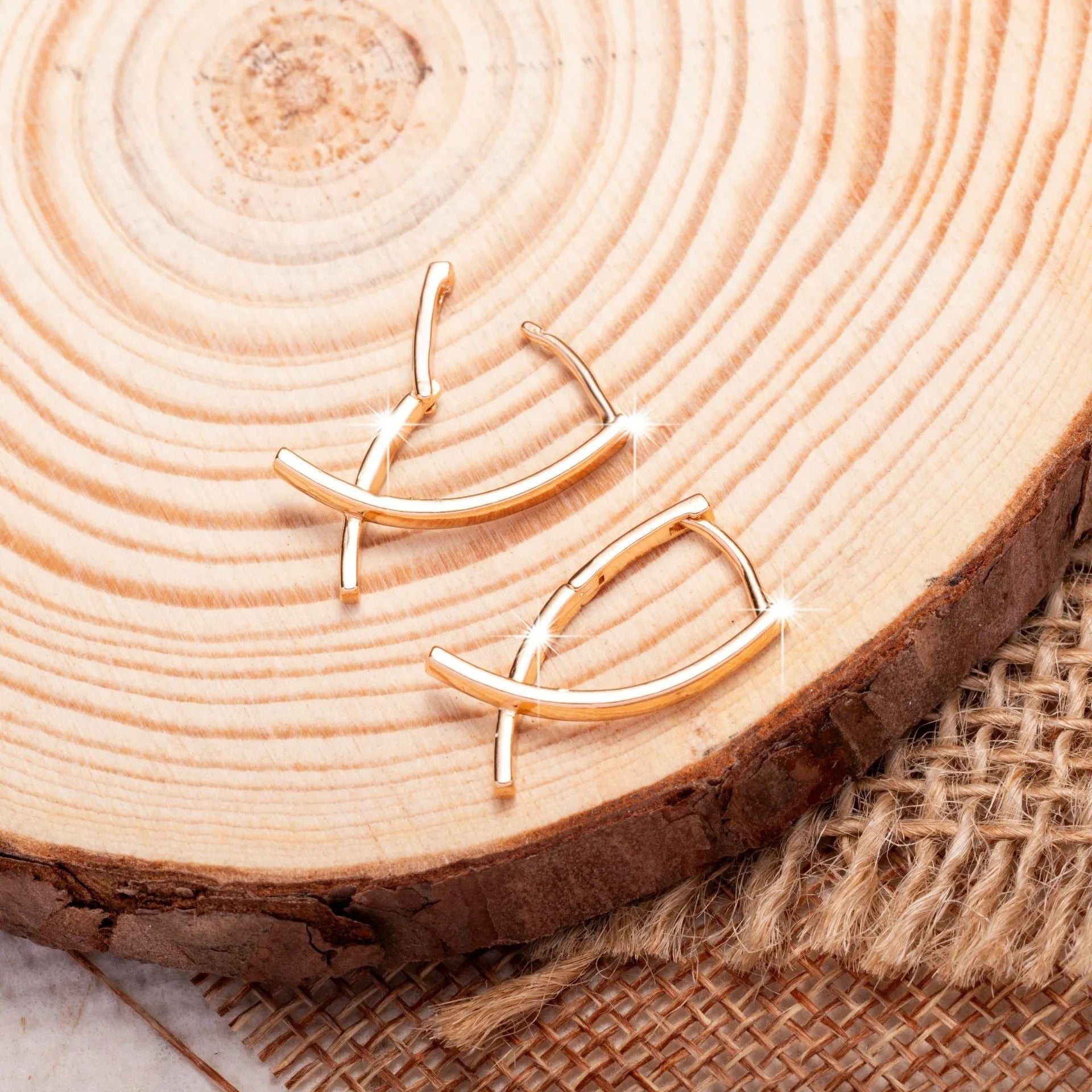 A pair of rose gold coloured cross pendant earrings on a copper base.