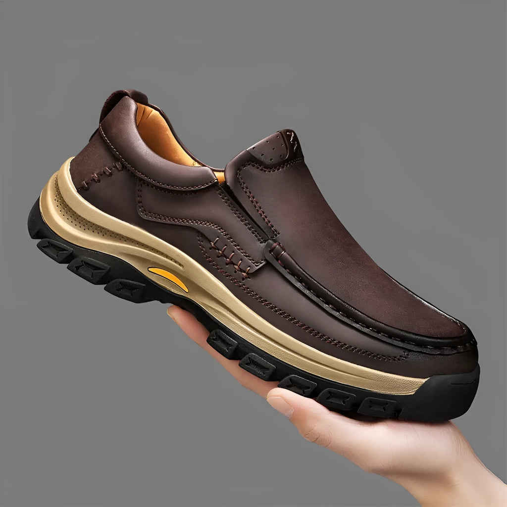 Men's black thick-soled mountaineering leather shoes with round toe and visible stitching on a natural background.