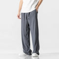 Man wearing beige straight-leg linen trousers with a drawstring waist, showcasing the cropped length and casual fit.