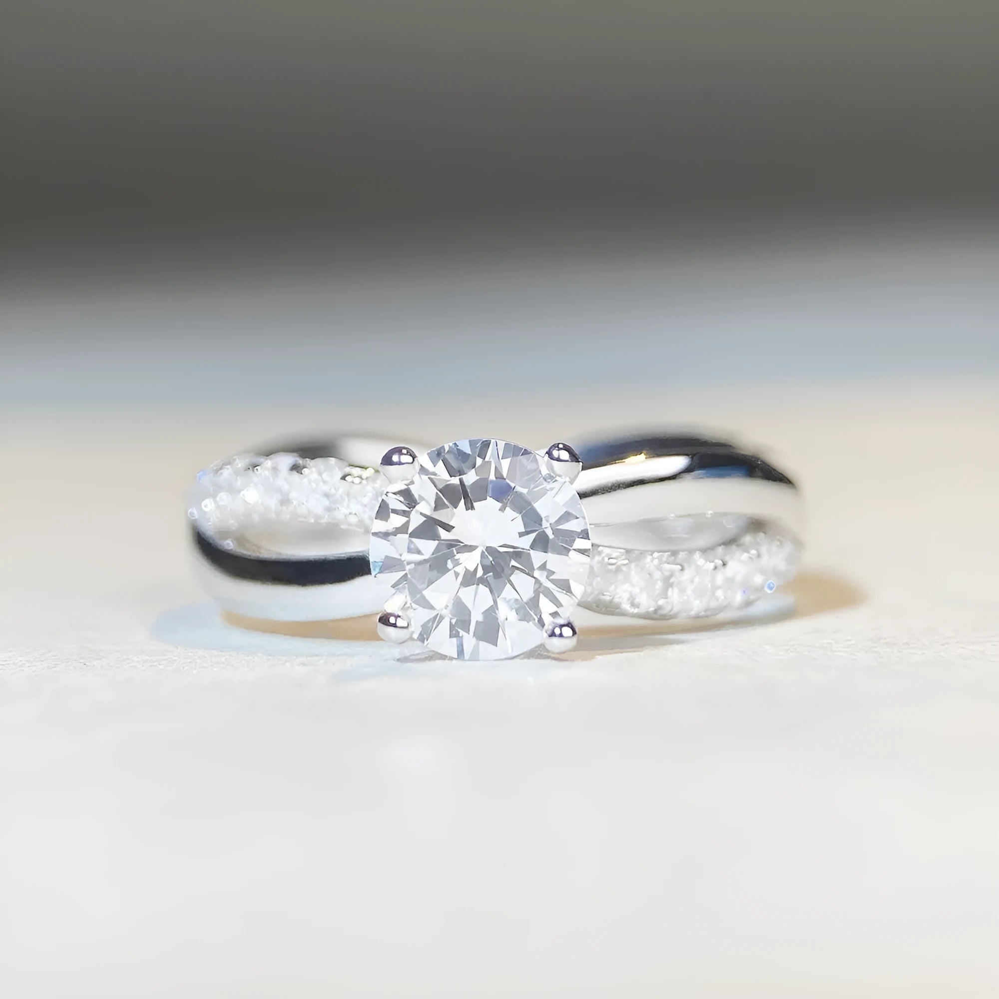 Geometric silver ring with a 1 karat moissanite in a four-claw setting, showing twisted band and cross design.