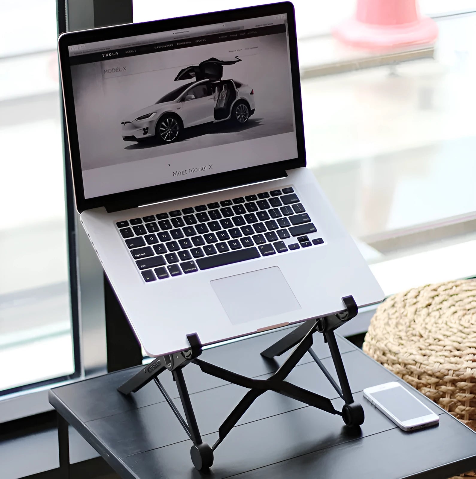 Black reinforced nylon folding laptop stand shown open in use and collapsed for storage.
