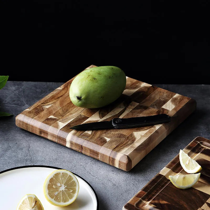 Brown parquet pattern solid acacia wood chopping board on a kitchen counter.