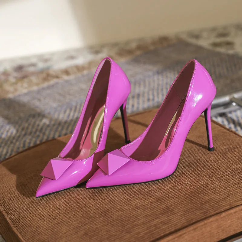 Pink patent leather women's high heels with pointed toe, stiletto heel, and buckle detail on a low-top design.