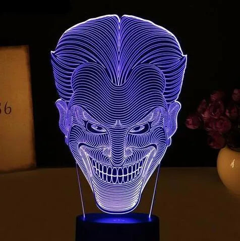 3D acrylic LED lamp displaying coloured light on a desk, with a remote control and USB cable